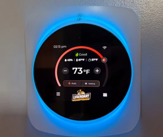 Legendary Service branded smart thermostat showing temperature, humidity, and heating mode