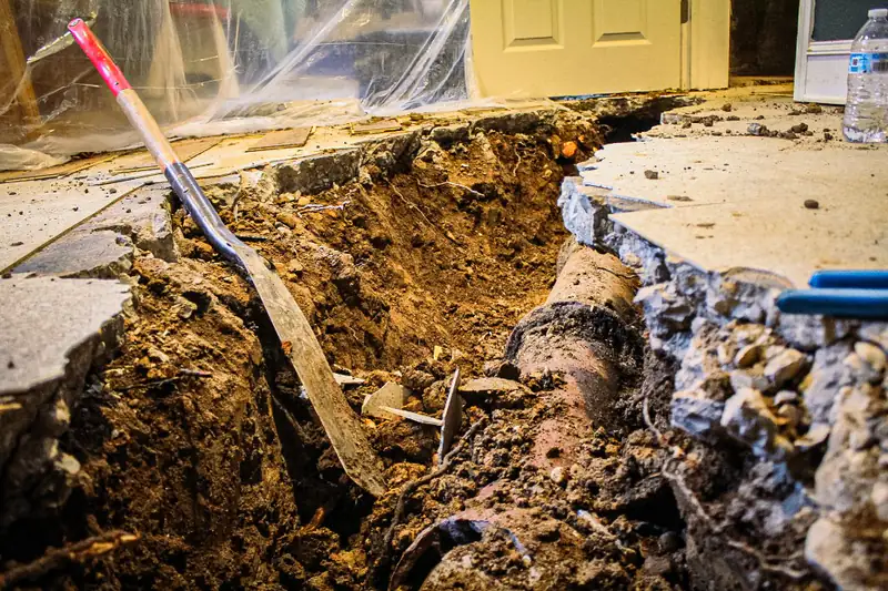 Excavated trench exposing an old sewer line inside a home during a Legendary Service repair